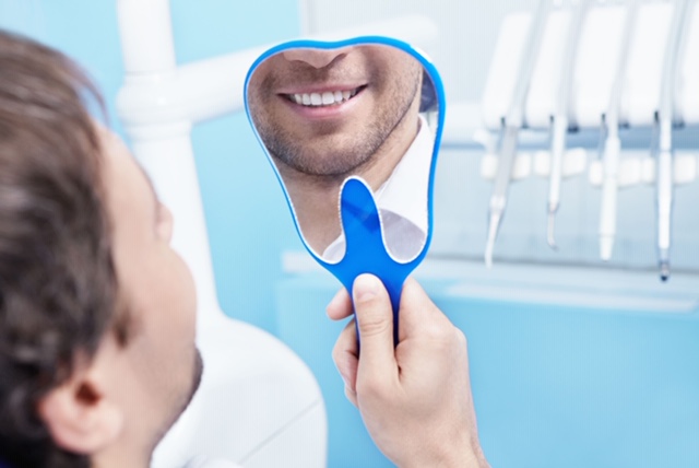 lachende man met handspiegel tandarts mondhygienist